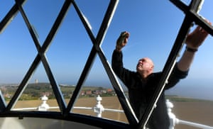 Keeper Chris Moore cleans the glass on the outside of the lantern room at Happisburgh Lighthouse