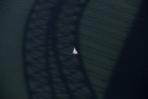 A boat sails under the shadow of the Sydney harbour bridge