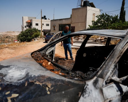 A man looks at a burnt car