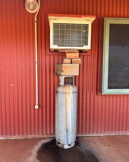 An air conditioning unit sits on a gas bottle and bricks to keep it in place at a social housing property in Roebourne