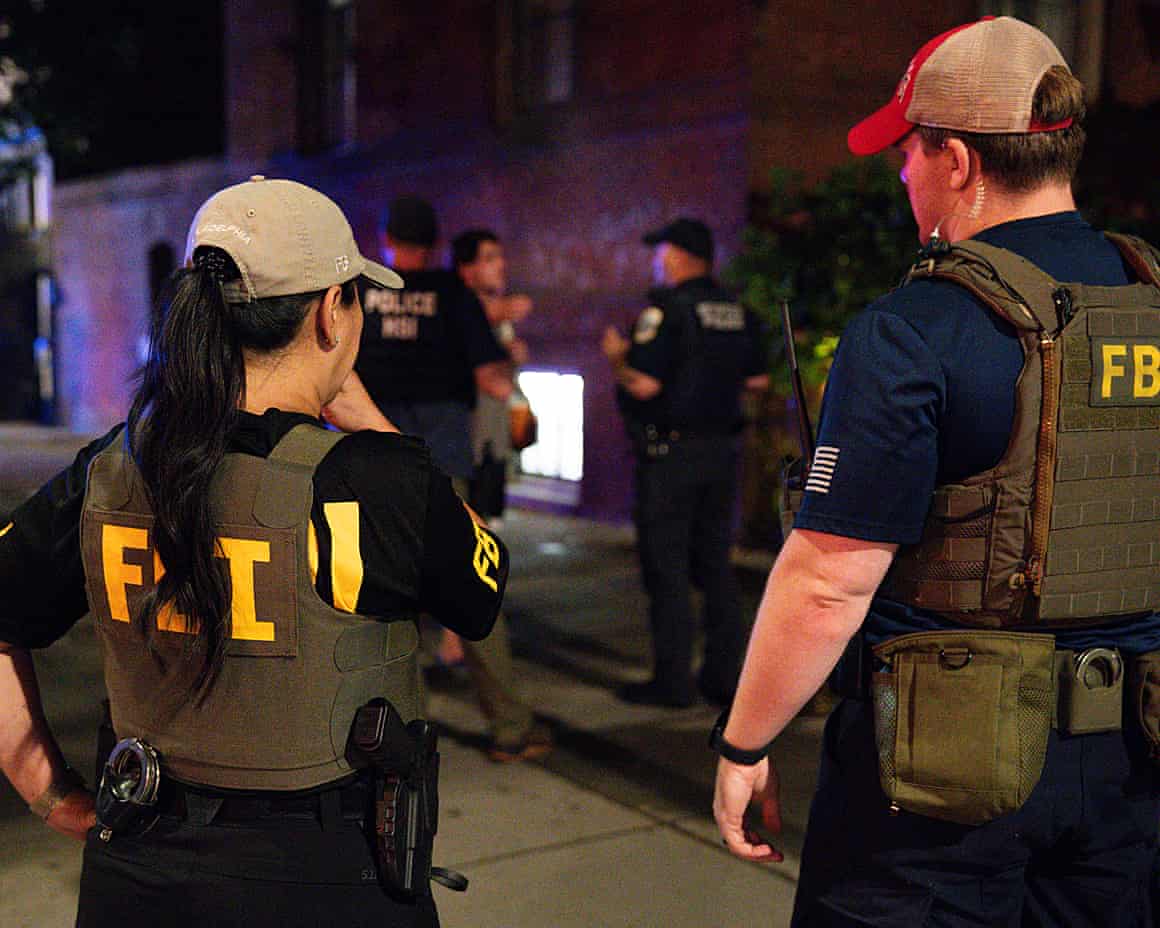 Two FBI officers stand at the scene of the destruction of property in a restaurant on 14th street in Washington