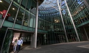 Two people walk through an empty office building complex in the City of London.