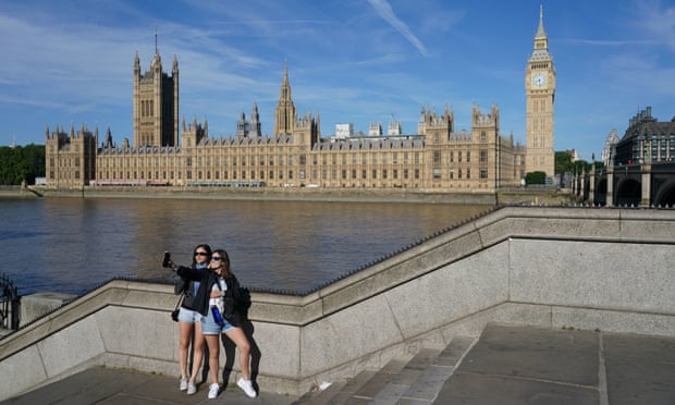 Two people take a selfie outside of Houses of Parliament in London