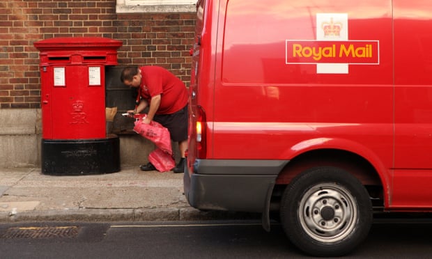 A Royal Mail employee empties a post box