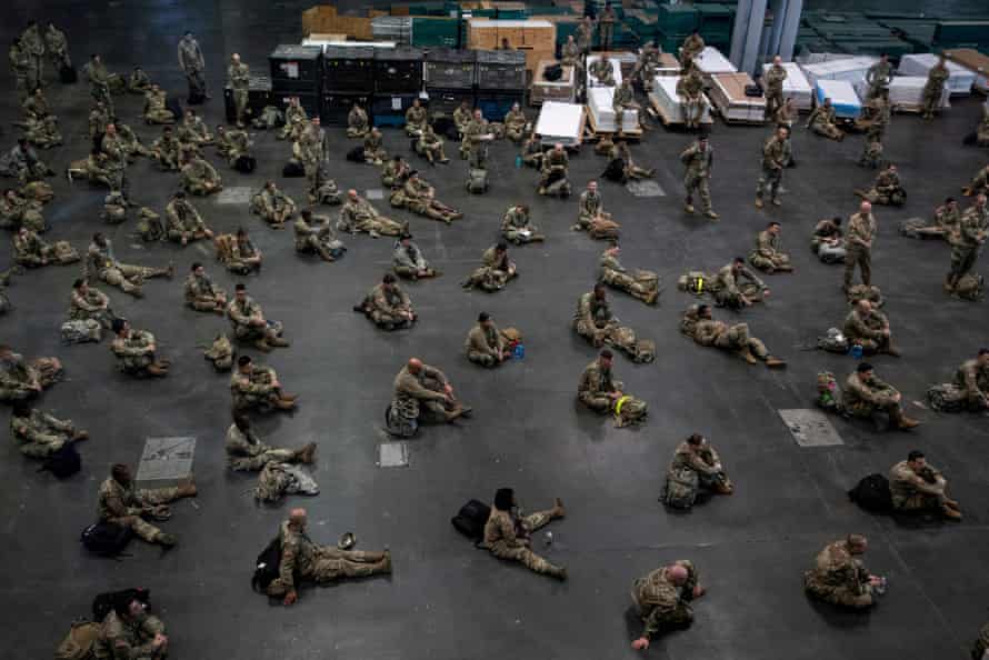 US Army personnel sit apart at the Jacob K Javits Convention Center in New York City, which will be partially converted into a hospital.