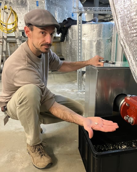 A man wearing a flat cap crouches beside a water cooling pipe