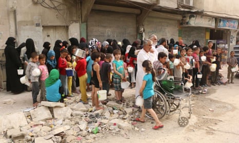 Displaced people queue up to receive aid food in Aleppo, Syria.