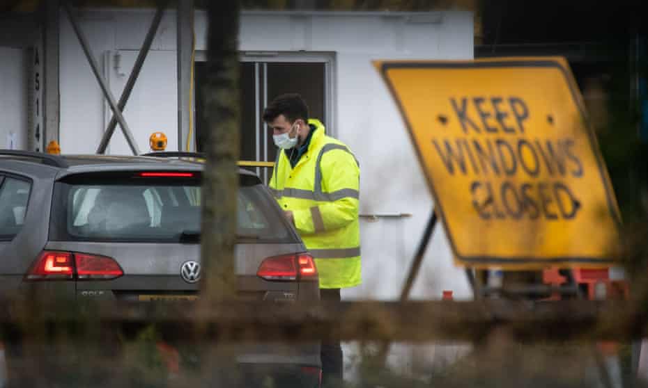 A medical worker speaks with an NHS worker as they attend a drive-through COVID-19 testing centre in a car park in London.