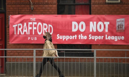 A woman passes a banner saying Trafford Pub do not support the ESL