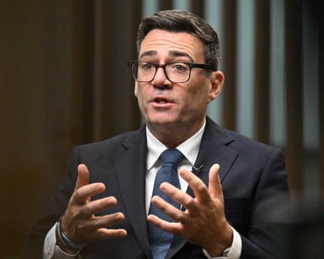 Prime Minister Andy Burnham gestures with both hands while speaking during an interview