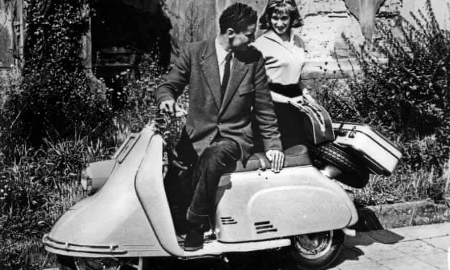 A couple on a Heinkel Tourist 103 A0 motor scooter, 1955 - 1957, with an unwheeled suitcase on the back.