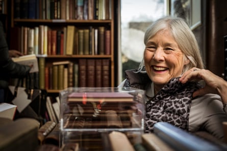 Jenny Dawes sits smiling with a tall bookshelf behind her.