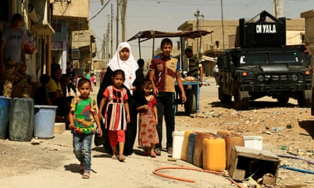 A family walk along a street in west Mosul.