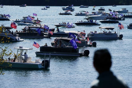Boats with US and Donald Trump flags cover the surface of a lake