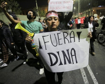 A woman holds a sign reading ‘Dina out’ in Lima