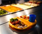 Kinderen in een Engelse schoolkantine met dienbladen en gezonde maaltijden