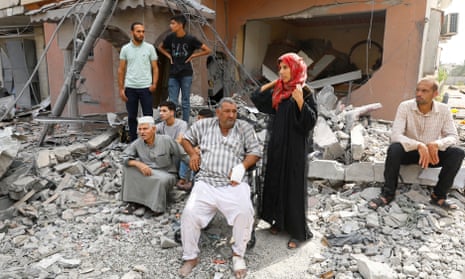 Palestinians watch the civil defence team as they search for victims trapped under the rubble of a house destroyed during Israeli strikes, in Khan Younis, in the southern Gaza Strip