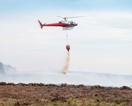 A helicopter drops water over the land.