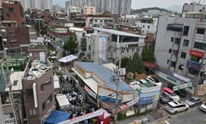Government officials wearing protective clothing stand under a white tent (centre L) to restrict access to the Sarang Jeil Church while the church’s lawyer holds a press conference on its latest COVID-19 cluster infection near the church in Seoul on August 17, 2020.
