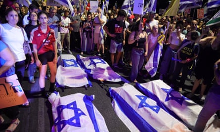 Coffins draped in Israeli flag with people around.