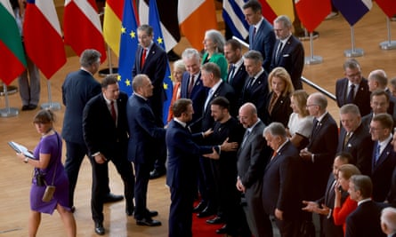 President of Ukraine Volodymyr Zelenskyy ( centre R) is greeted by French President Emmanuel Macron with lots of flags and people, mainly men, in picture