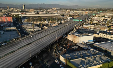 Overhead photo taken in slanting morning or evening sunlight of empty highway above industrial area.