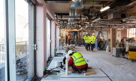 Workers in hard hats at work on a high floor of a half-completed, newly glazed office building