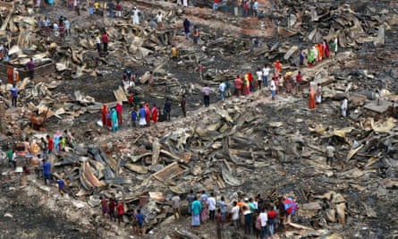 People survey the wreckage after a shanty town fire in Dhaka.