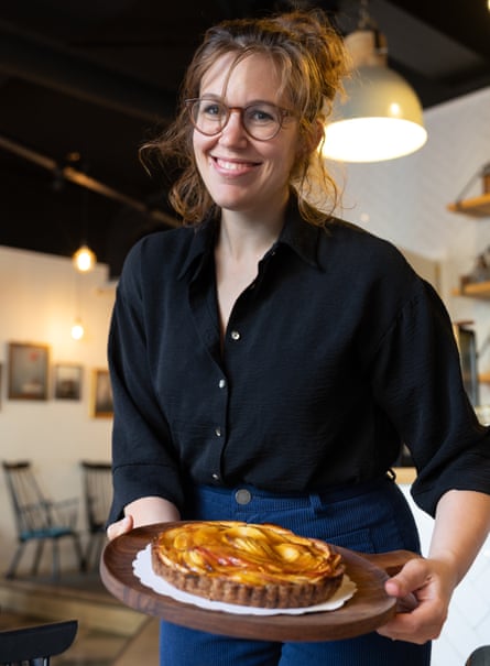 A smiling woman holding an apple cake on a tray
