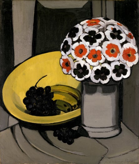 A vase of white, black and red flowers next to a yellow bowl holding black grapes