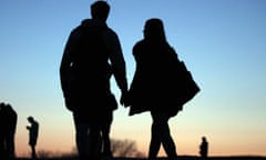 A couple in silhouette holding hands