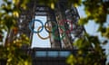 The Olympic rings are seen on a section of the Eiffel Tower with trees in the foreground