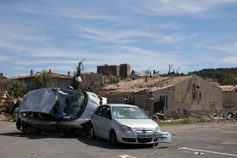 Damaged homes and a wrecked car on its side.