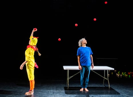 Kati Ylä-Hokkala, dressed in a chicken suit, throws a line of red balls over the head of Sean Gandini.