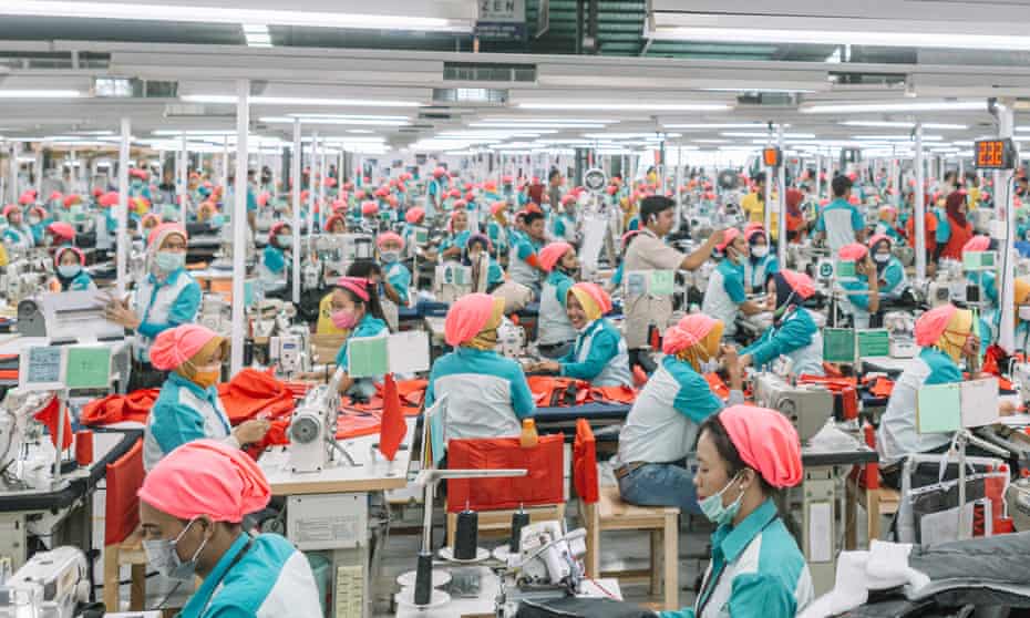 Hundreds of workers, identically clad, operate sewing machines at a garment factory