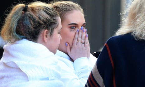 Three girls standing together after the Manchester bombing, one with her hands on her face, visibly distressed