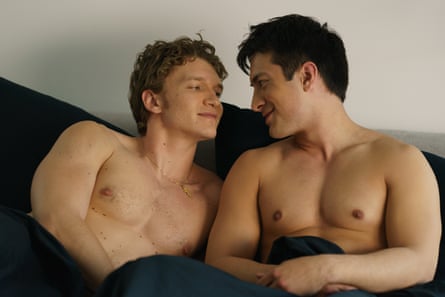 Two naked men snuggle up in bed