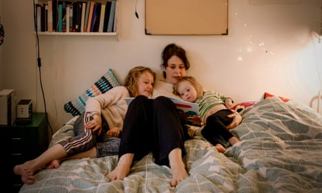A mother reads to two children on bed