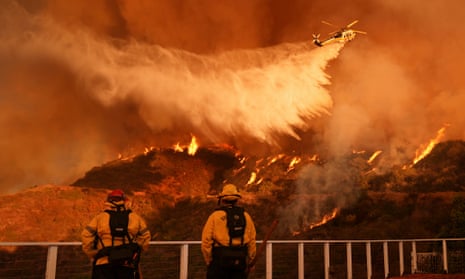Firefighters watch as water is dropped on the Palisades Fire in Mandeville Canyon Saturday, Jan. 11, 2025, in Los Angeles. (AP Photo/Jae C. Hong)