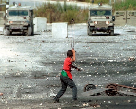 A Palestinian demonstrator uses a slingshot to throw stones at IDF vehicles on the outskirts of Ramallah, West Bank, September 2001.