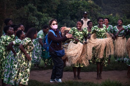 A tourist dances with a group of women dressed in matching dresses and grass skirts