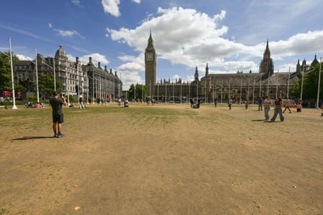 A person takes a photo on a phone looking across Parliament Square towards parliament and Big Ben.