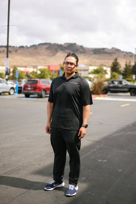 A young man wearing athletic clothes and glasses stands in a parking lot