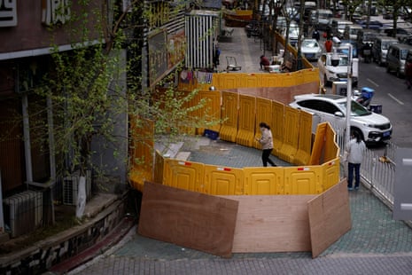 A woman wearing a face mask is seen at a residential area blocked by barriers in Wuhan, Hubei province. 