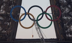 Workers hang the Olympic rings symbol on the Eiffel Tower