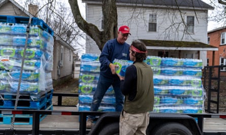 Two men unload bottled water from a truck