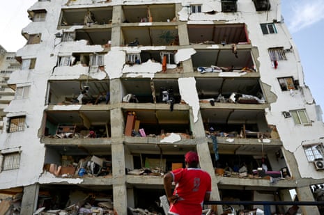 A man looks at a damaged high-rise building in the aftermath of earthquakes in La Guaira.