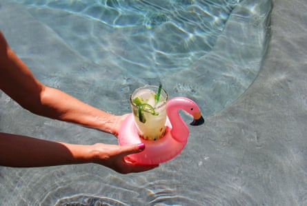Someone successful a excavation holding a cocktail successful an inflatable flamingo drinks holder