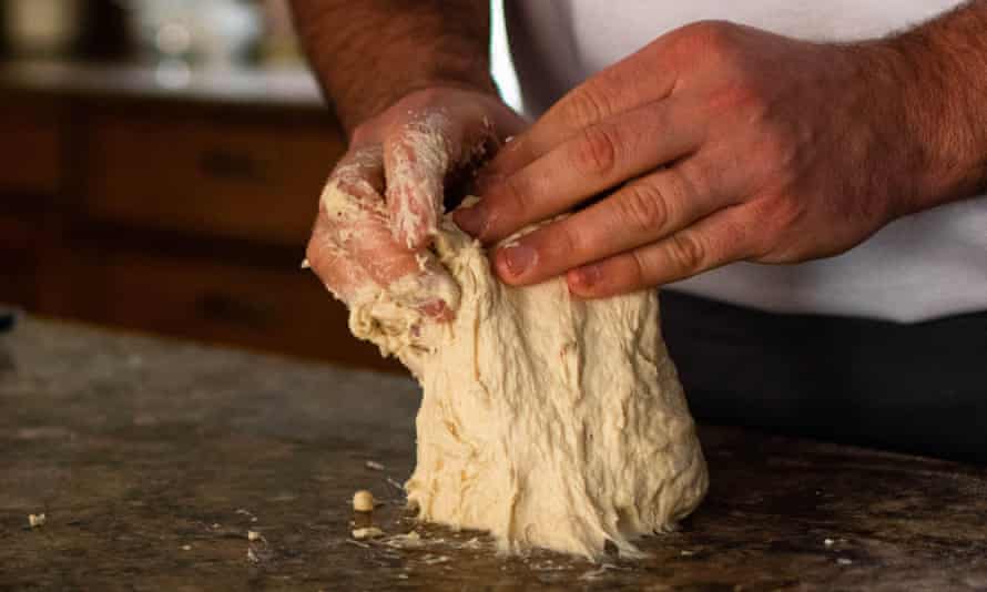 A man's hands kneading bread dough