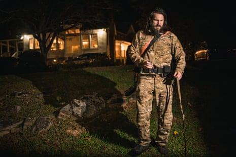 A man in camo stands in front of his home at night